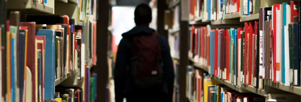 A student walking through the library stacks