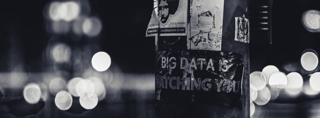 A sign on a street lamp says "Big data is watching you"