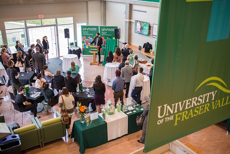A photo shows students attending an alumni event at the University of the Fraser Valley, as a member of the alumni association delivers a speech.