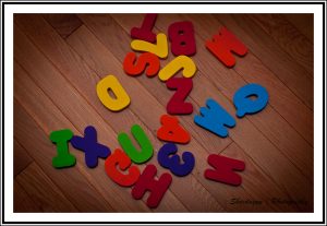 Colorful children's wood letters are scattered on a wood floor.