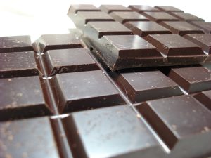 Two larges pieces of milk chocolate bars with a small square pattern are laid on top of each other.
