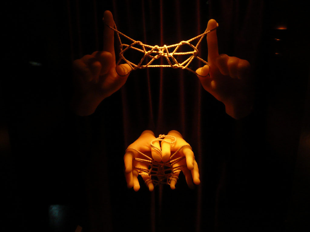 Four hands holding twisted ropes