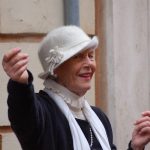 Elderly woman in a white hat.
