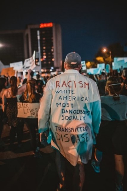 Man wearing a shirt with an anti-racist slogan written on the back