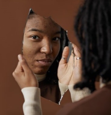 reflection of a woman looking a large piece of broken mirror