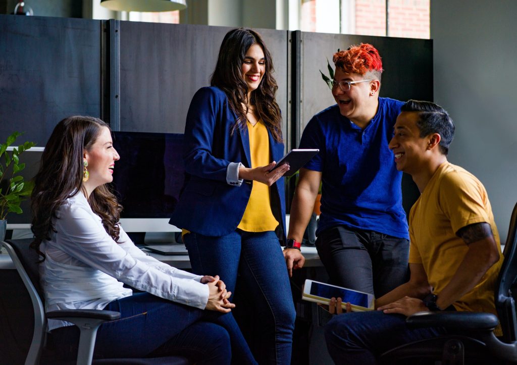 Group of four people sitting and standing looking at their devices