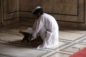 A photograph of a young boy reading the Quran in a Mosque