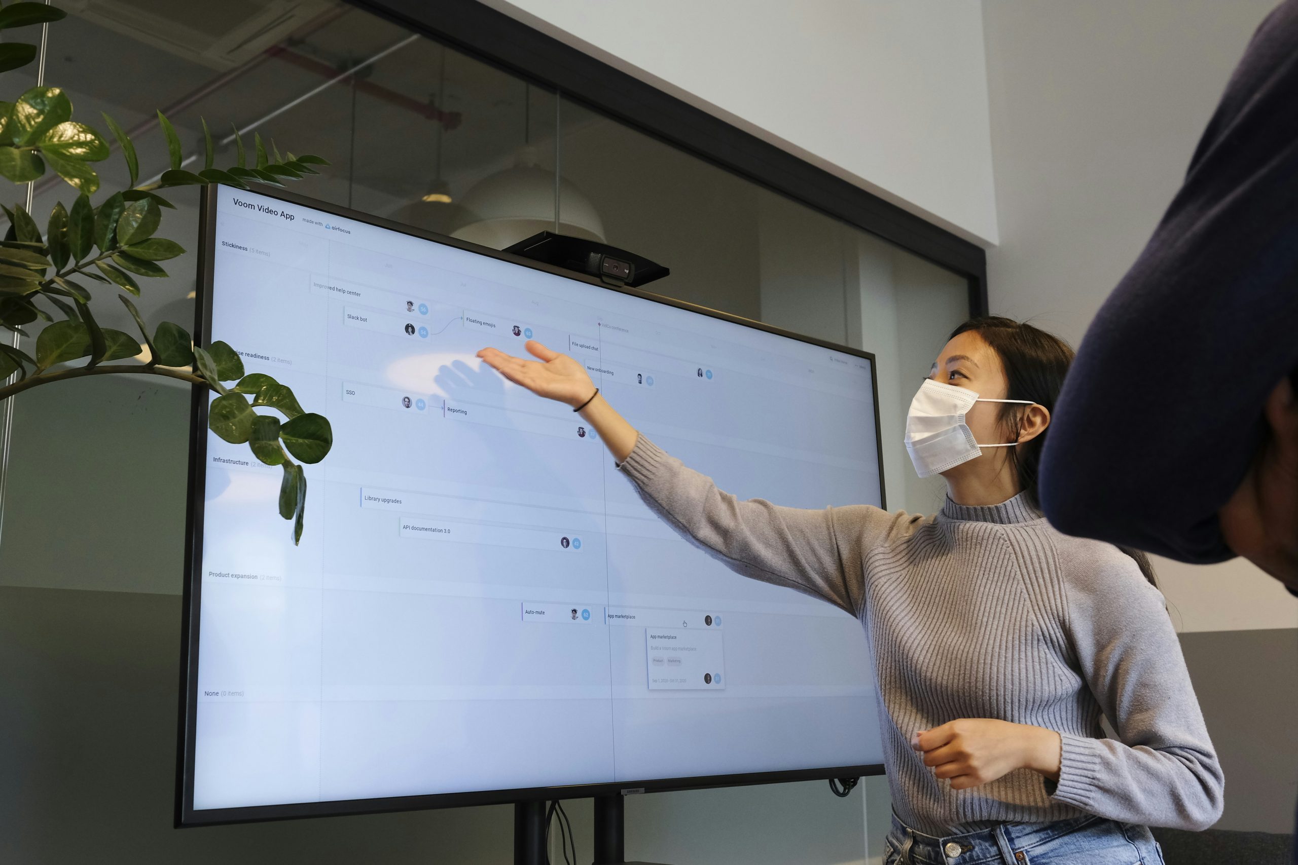 Woman with a mask on is giving a presentation.