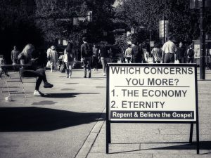 A sign says "Which concerns you more? The economy or eternity. Repent and believe the gospel."