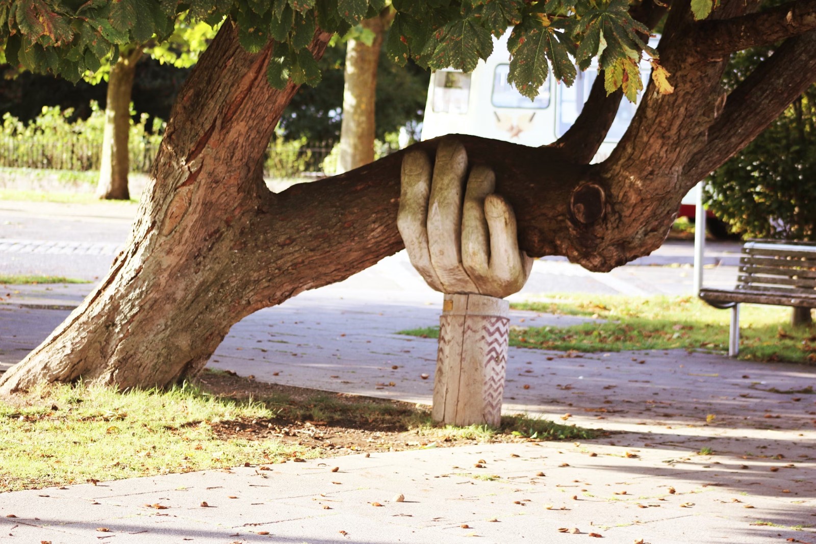 A stone sculpture of a hand holds up a large tree branch