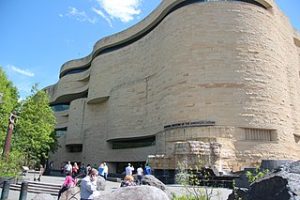 A wavy building with people walking around.