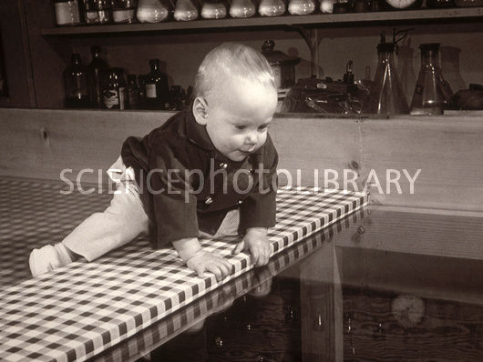 black and white photo of baby approaching the edge of a table