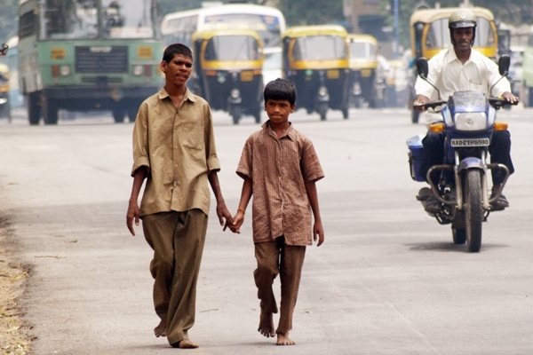 photo of two boys holding hands walking down the street