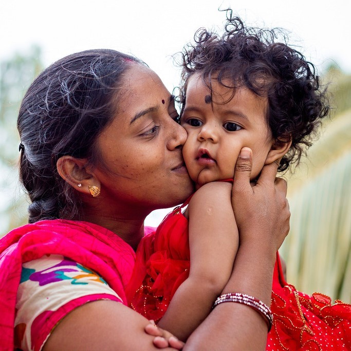 Photo of a mother holding and kissing her toddler