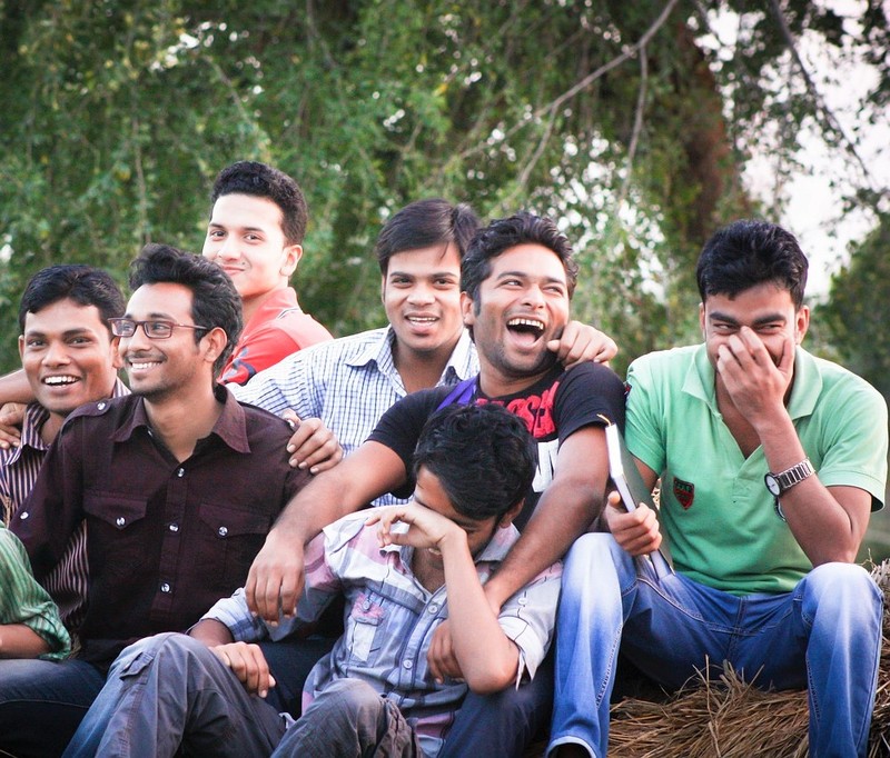 A group of young men sit together laughing and smiling