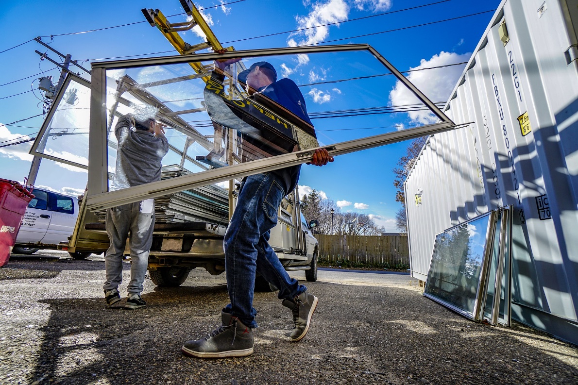 Photo of construction employees loading window panes into the back of a truck.