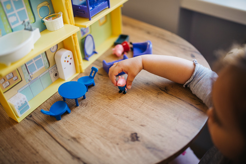 Photo of a small girl playing with a dollhouse.