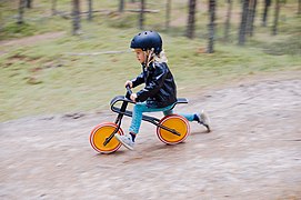 A photograph of a child going fast downhill on a bicycle