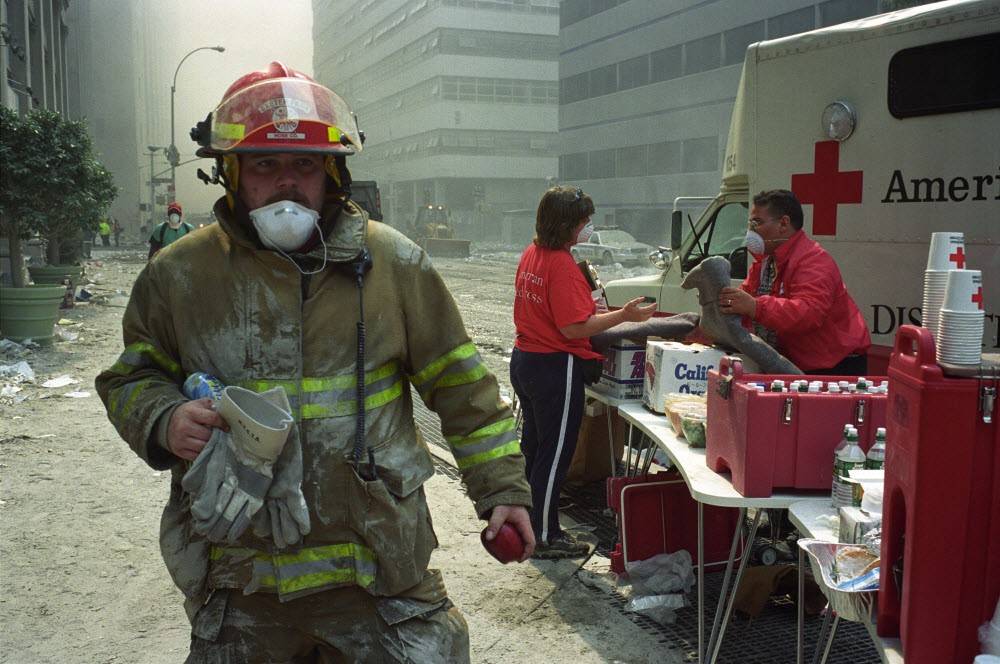 image of a firefighter (uncredited) and two Red Cross volunteers at the Ground Zero site in New York City, after 9/11.