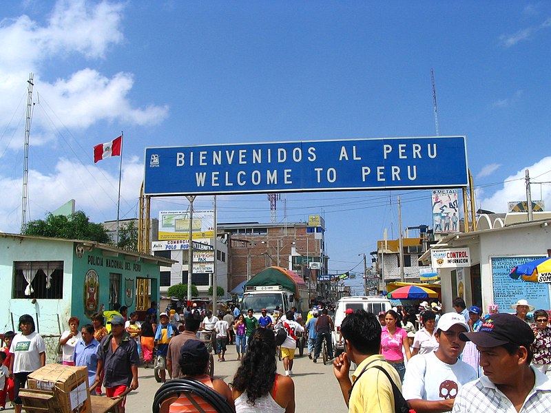 Sign welcoming people entering Peru from Ecuador along a busy street