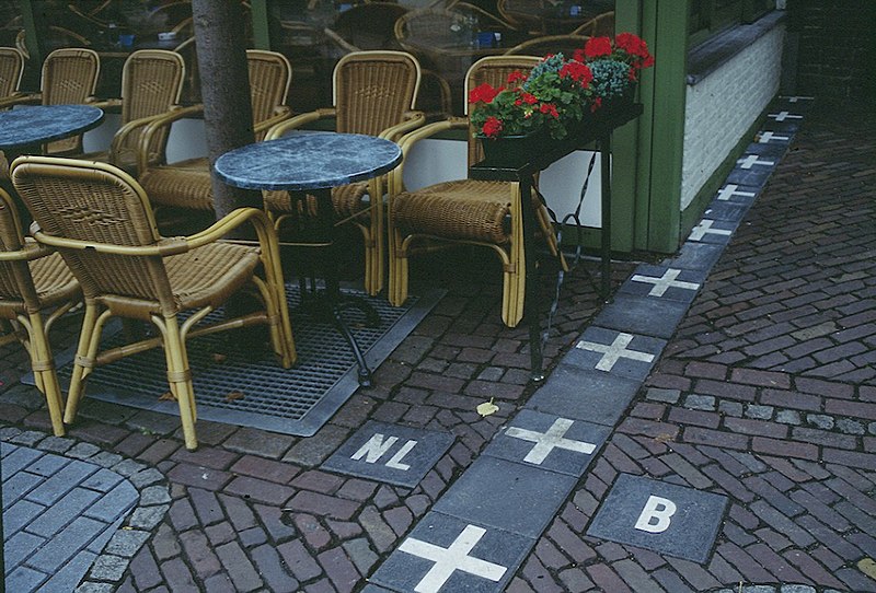 Netherlands/Belgium border outside of a restaurant, showing cobblestone and simple markings on the ground, with no walls or fences