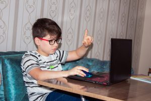 Child interacting with teacher through web conferencing application.