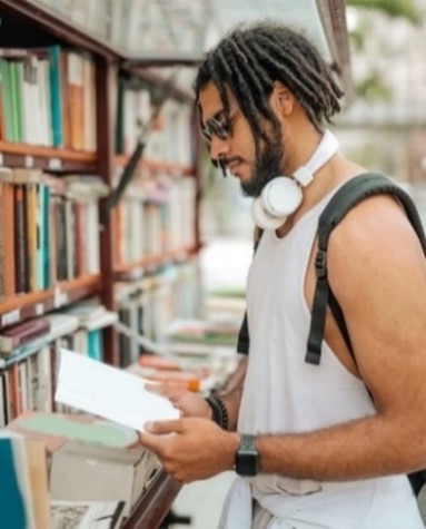 Ethnic man with dreadlocks reading a book on the street