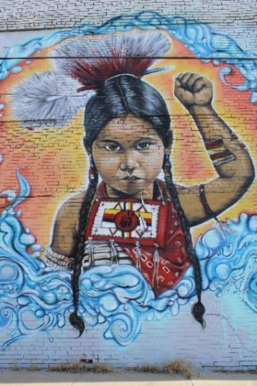 Building mural of young Native American child holding their fist in the air