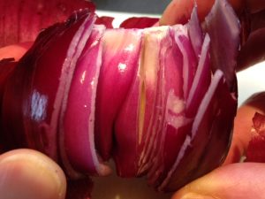 In this image, an onion is being peeled by pulling apart the various layers, from outside to inside.