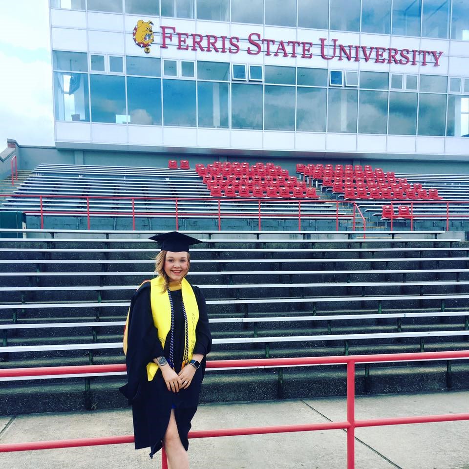 color photography of Chapter 6 author, Linsdey Bronold, wearing her graduation cap and gown in front of the Ferris pressbox