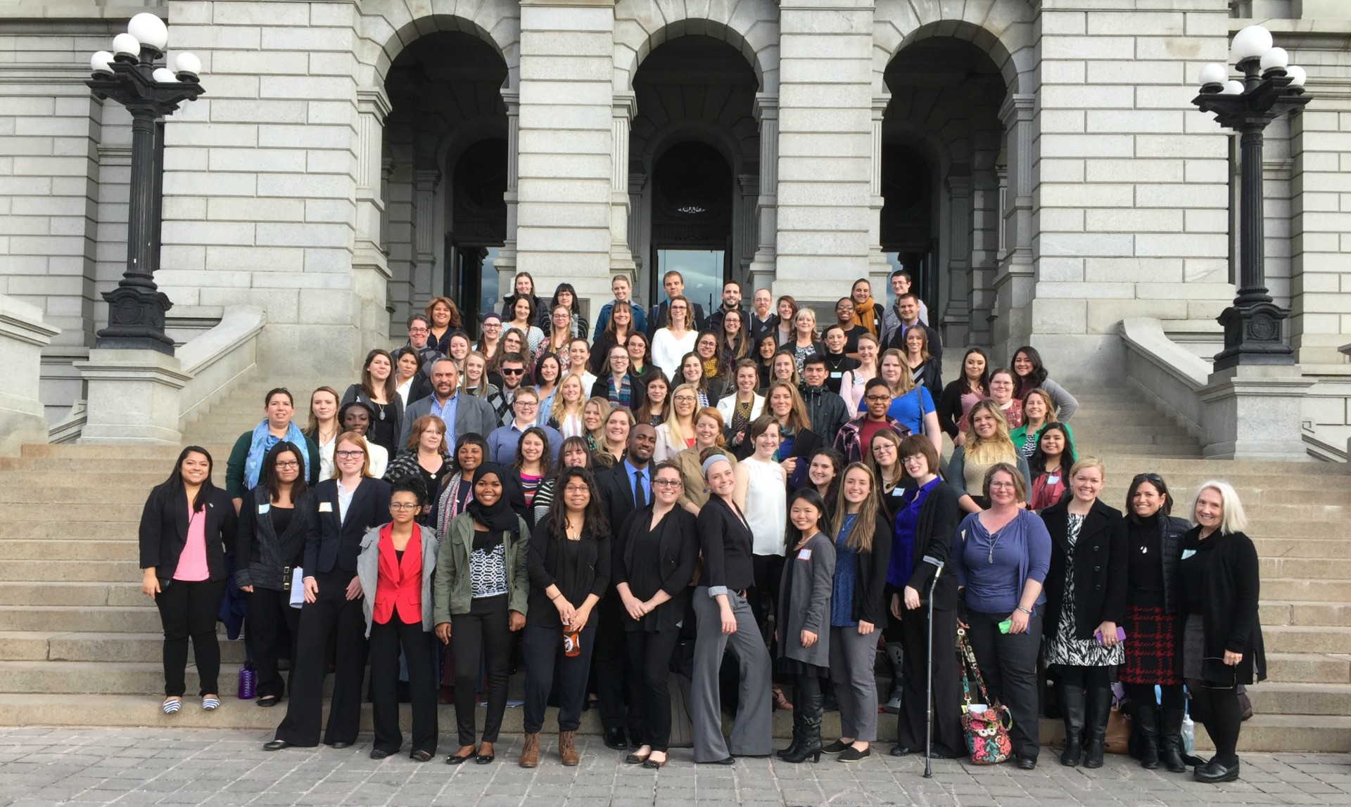 color photography of a large group of people standing in front of a government-looking building