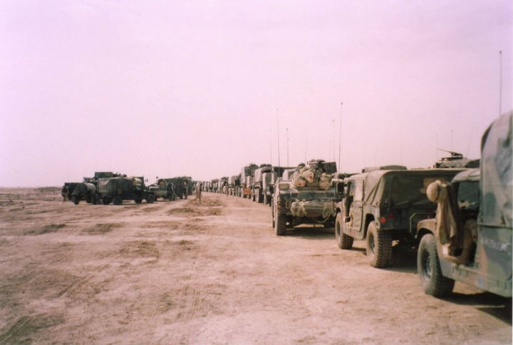 Photo by Brian Majszak (co-author}. Long line of military vehicles in a desert environment.