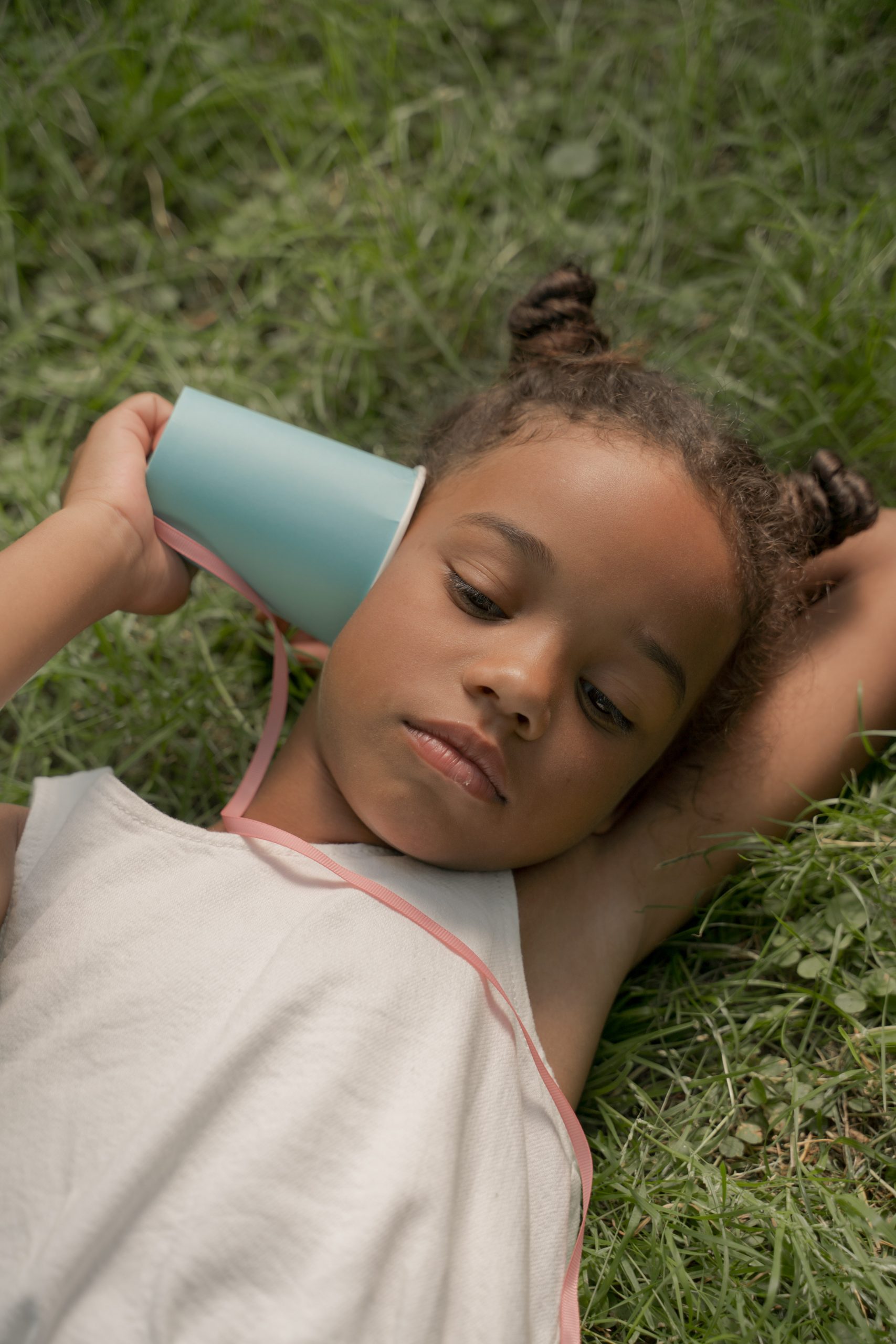 Young girl with a homemade telephone made of a paper cup and string