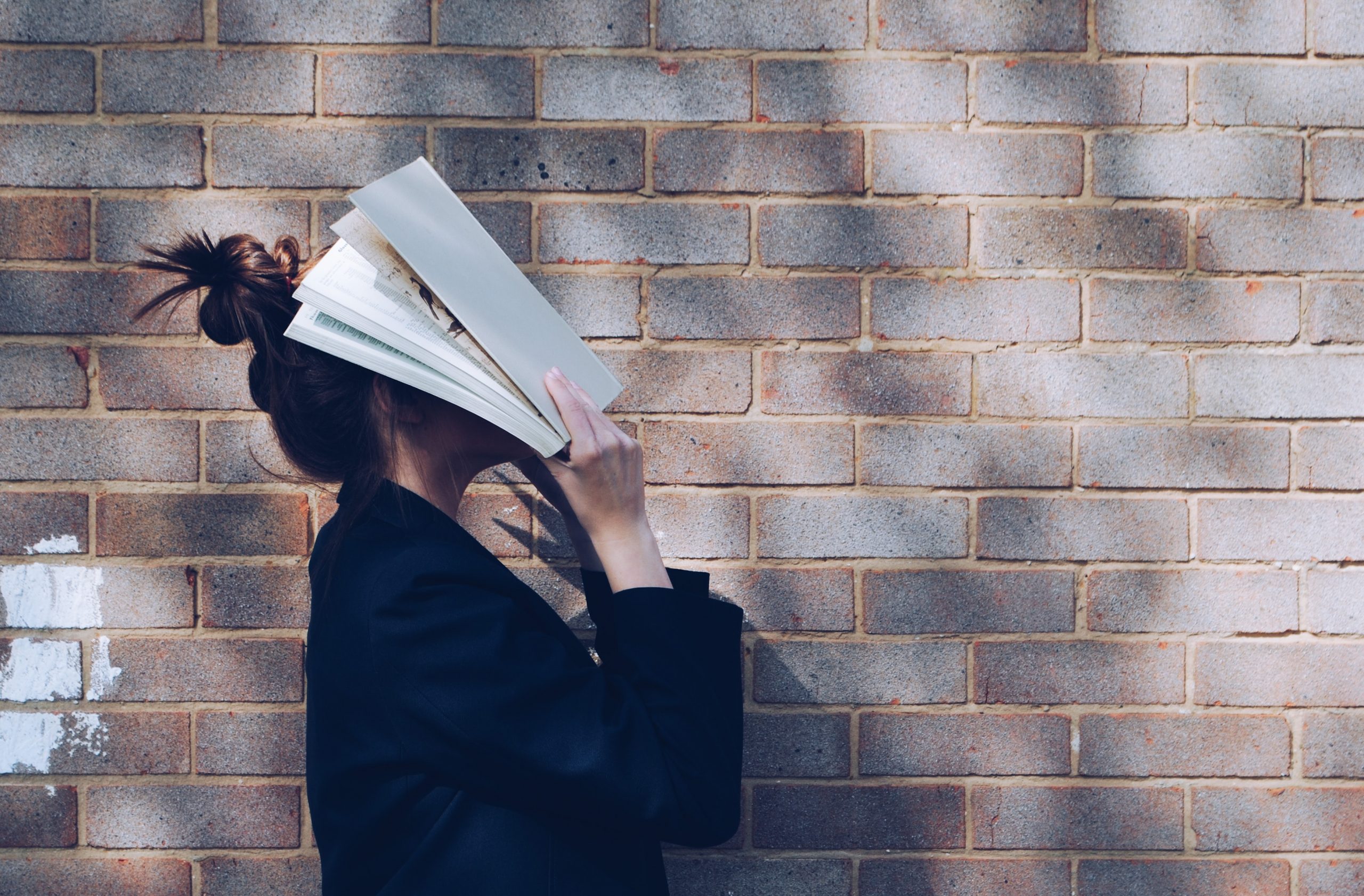 A woman with a textbook over her head in frustration