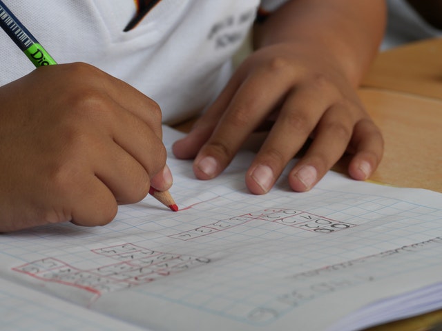 Young student completing math problem on paper with pencil