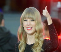 Taylor Swift giving a thumbs up to a crowd.