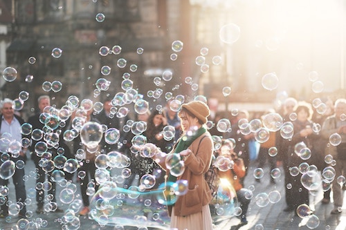Young woman entertains crowd on street by blowing bubbles