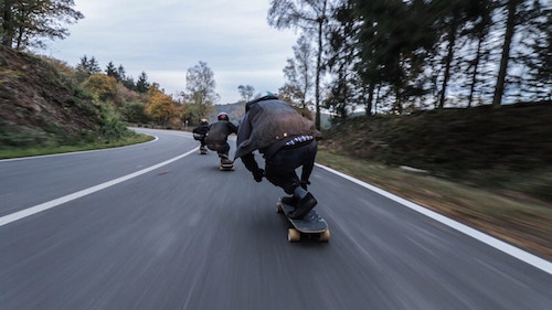 Skateboarders on the curve of a 2-lane highway