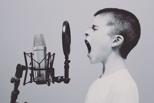 Young boy loudly vocalizing into studio microphone