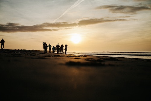 Six people in silhouette on a beach at sunset