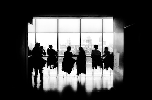 Silhouette of people sitting at boardroom table