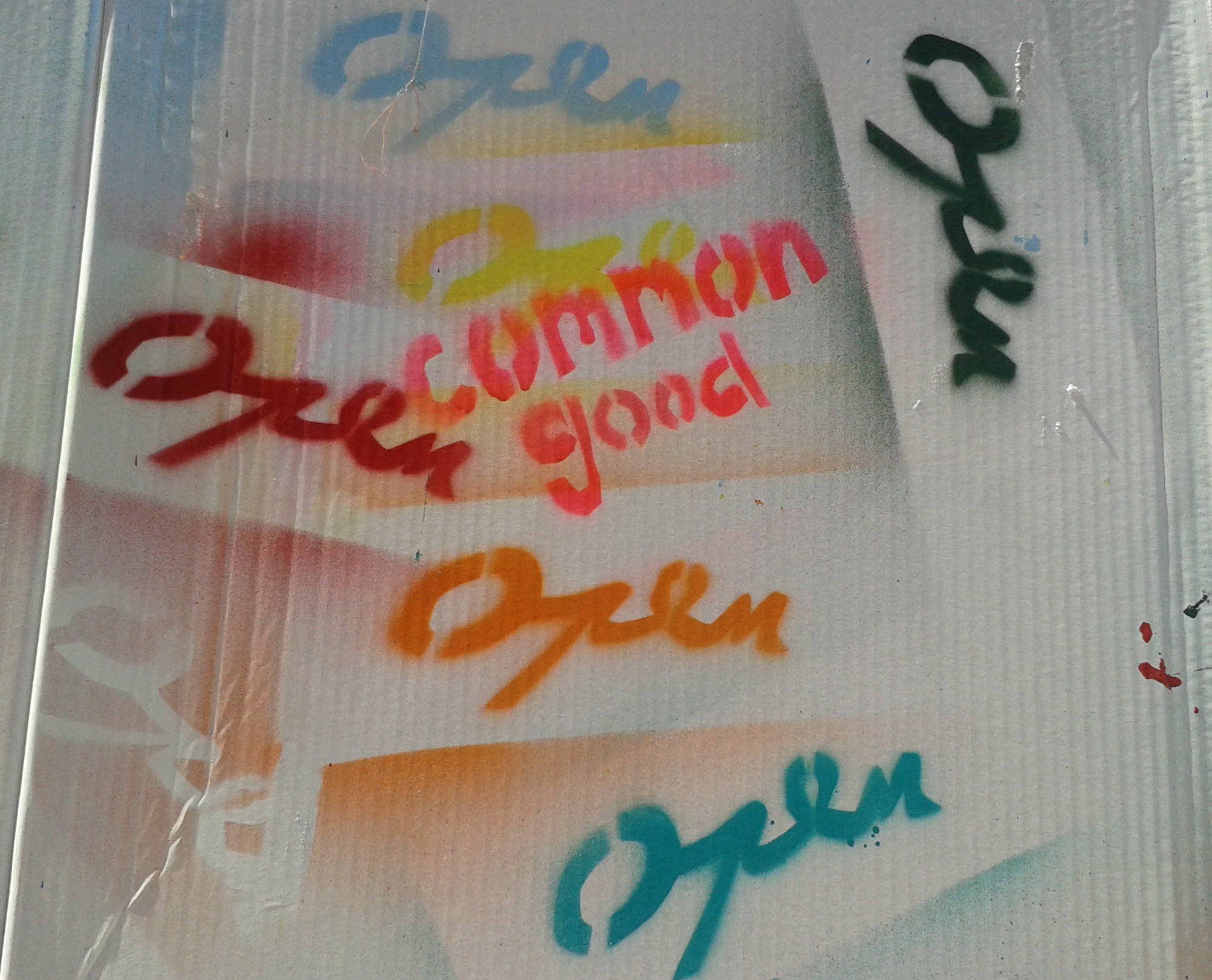 Graffiti with words "open" in different colours and "common good" in orange