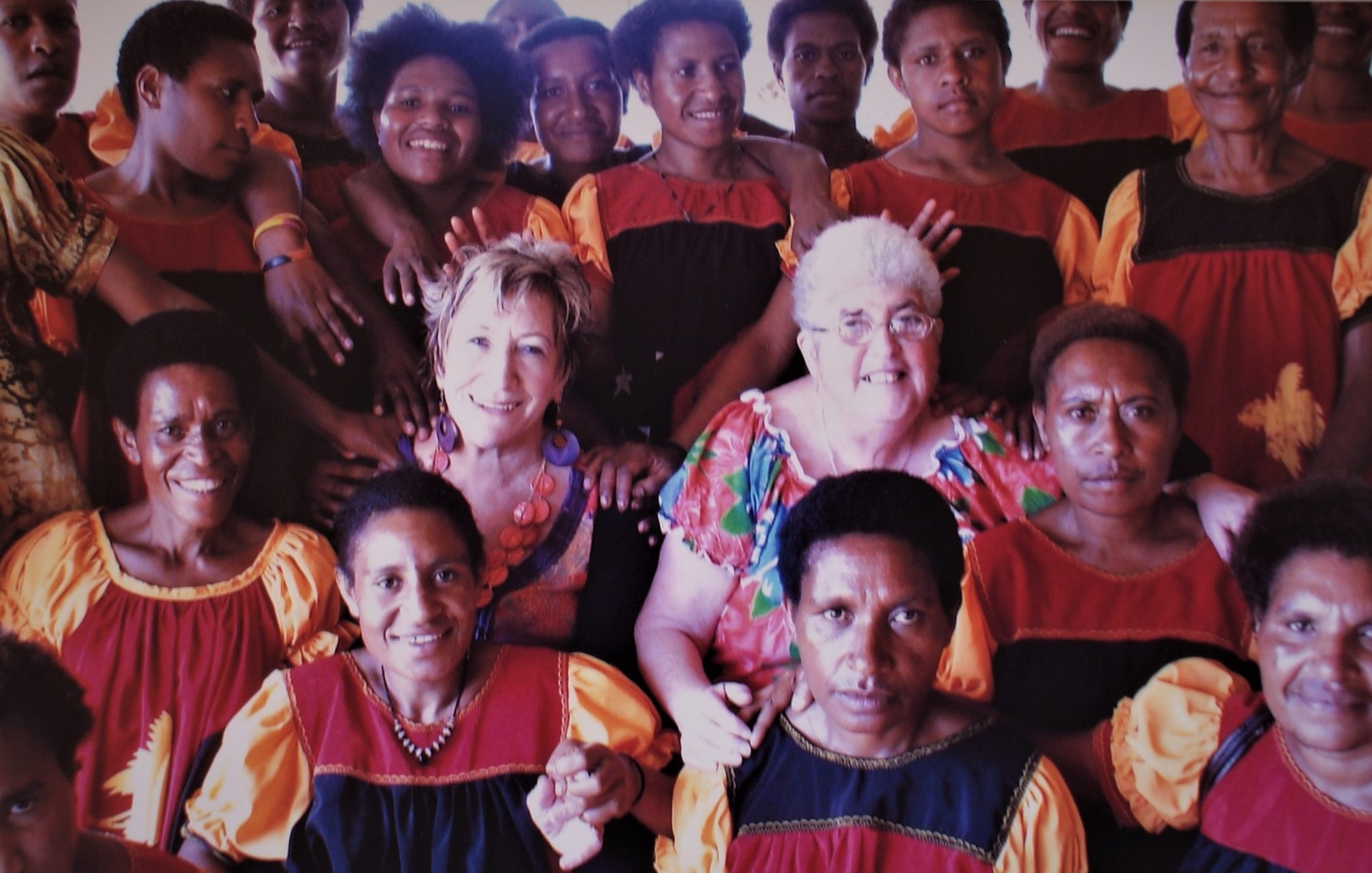 Lesley and a friend are sitting surrounded by a group of about 15 Fijian women.