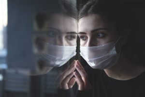 Girl wearing a mask looking out a window