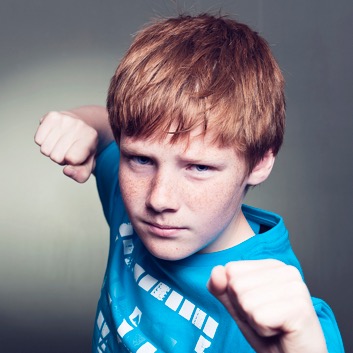 Young boy with clenched fists looking ready to fight.