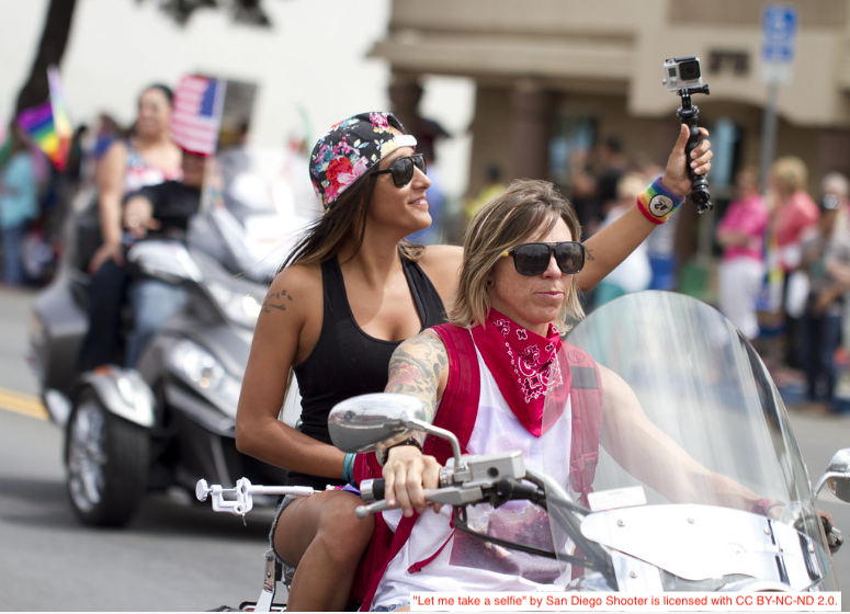 Woman taking selfie on motorcycle in Pride parade