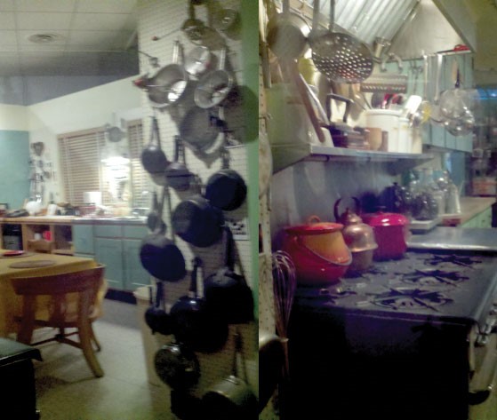 picture of a kitchen with many pots and pans organized on a pegboard