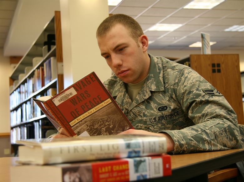 a man in an army uniform reads a book in a library