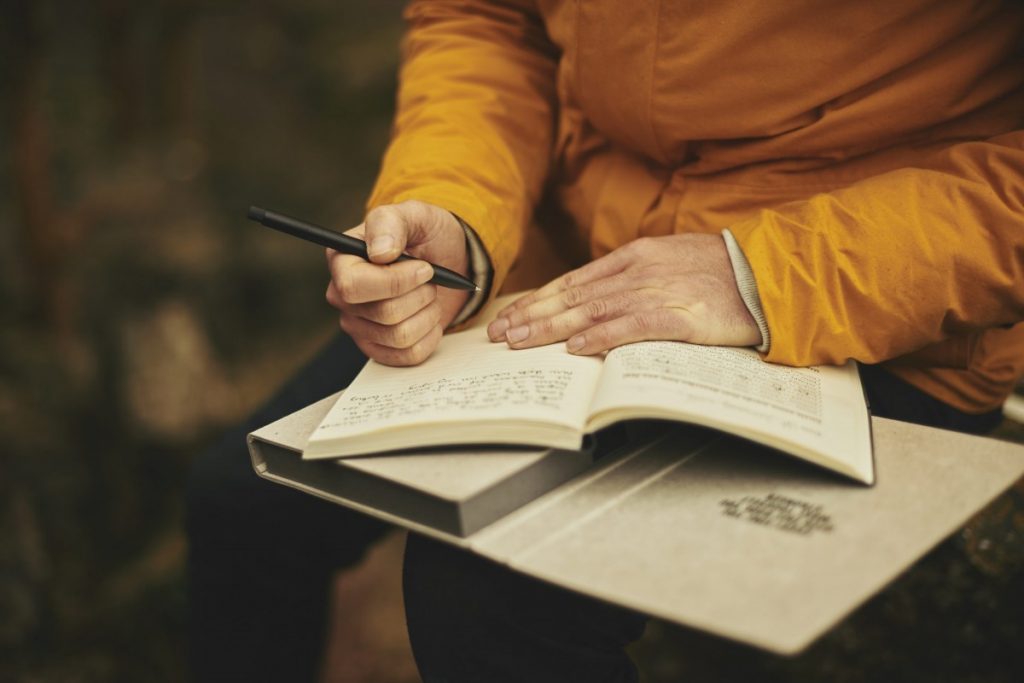 a person writing down notes in a journal while seated