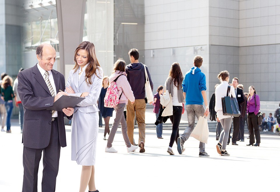 two people filling out a clipboard survey in a crowd of people